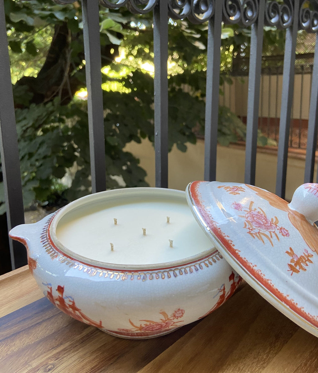 Vela en sopera de cerámica en tonalidades naranjas.