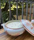 Vela en sopera de cerámica en tonalidades naranjas.
