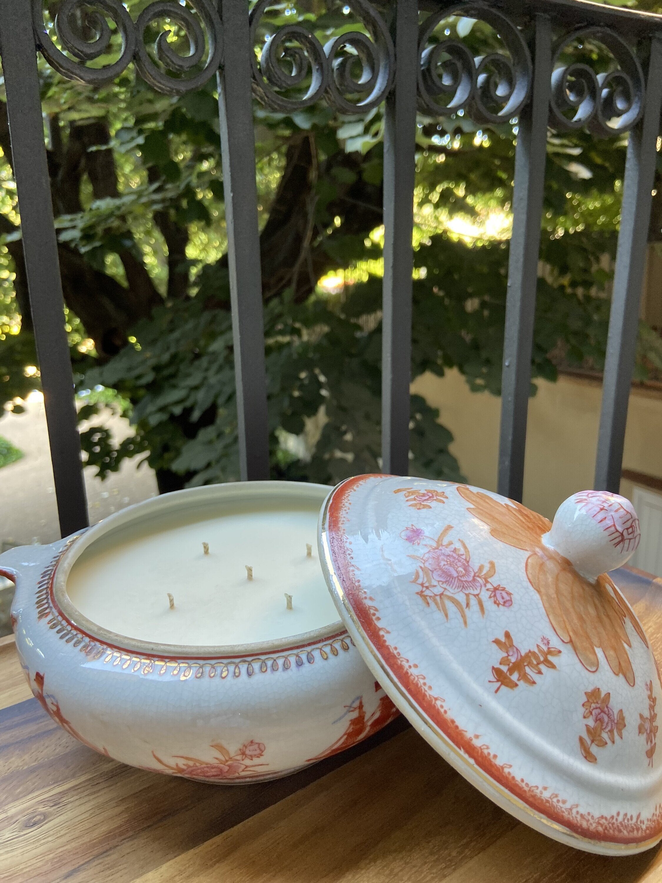 Vela en sopera de cerámica en tonalidades naranjas.